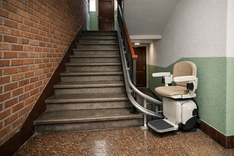 Silla salvaescaleras en la escalera de un bloque de pisos de ladrillo