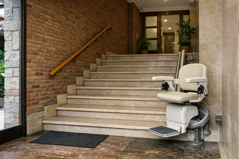 Silla salvaescaleras en la escalera ancha de un portal de ladrillo